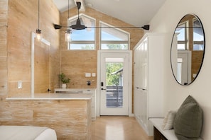 A modern bathroom with a wooden accent wall, a large mirror, and a built-in sink. - Luxe Austin Haven |H-Tub | Ping Pong | w/Bungalow (Austin)