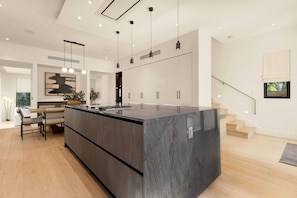 Une cuisine moderne dotée d’un îlot central, de luminaires suspendus et d’un escalier menant à un niveau supérieur.