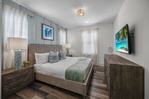 Ein modernes Schlafzimmer mit einem Bett, Nachttischen, einer Kommode und einem Gemälde an der Wand.