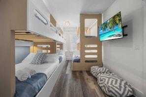 A compact hotel room with bunk beds, a flat-screen TV, and a view of the hallway. - Santa Rosa Boho Villa | Game | Designs | Beach (Santa Rosa Beach)