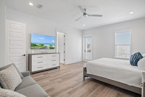 Ein Schlafzimmer mit Bett, Fernseher, Deckenventilator und Blick ins Freie.