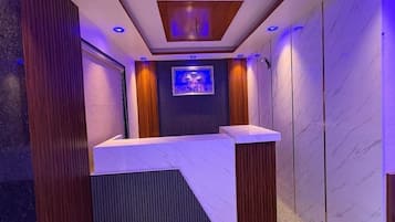 A reception area with a marble counter, a television screen, and a ceiling with recessed lighting.
