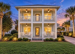 A two-story house with a balcony on each floor, a front porch with chairs, and a well-maintained lawn. - 4BR Santa Rosa Beach & Lake Getaway (Santa Rosa Beach)