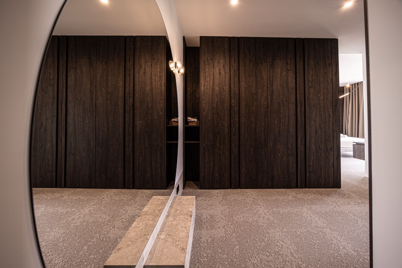 Una camera moderna con pannelli in legno scuro, una struttura bianca a forma di arco e pavimento rivestito di moquette.