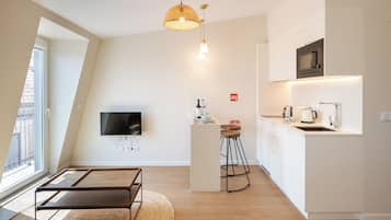 A modern kitchen with a flat-screen TV, a microwave, and a coffee maker.