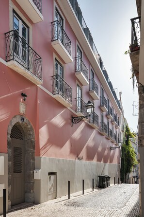 A building with multiple balconies, a stone entrance, and a cobblestone street. - Cordoeiros Studio & Apartments (Lisboa)