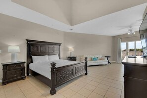 A spacious bedroom with a large bed, a white sofa, and a balcony view. - 3 Story Destin Villa | Private Beach | Shared Pool (Destin)