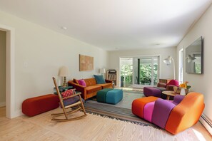 En moderne stue med sofa, stole, en gyngestol og et sofabord.