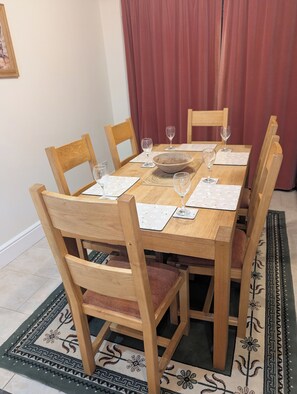 Una mesa de comedor con sillas de madera, un tazón grande y copas de vino.