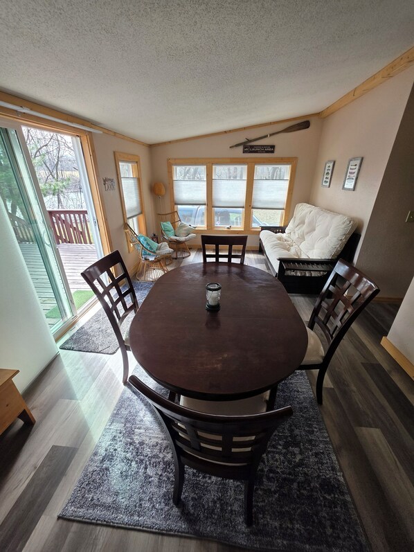 A dining area with a round table, four chairs, a rug, and a view of the outside through large windows. - Private Home,1+acre property,close to WIDells/CastleRock,FirePit,yard games,wood (Adams)
