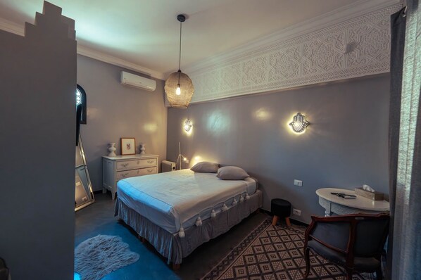 A bedroom with a bed, bedside tables, a desk, and a chair.