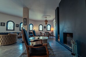 A spacious living room with a fireplace, a round table, and comfortable seating.