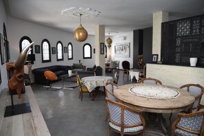 Ein geräumiger Wohnbereich mit einem runden Holztisch, gemusterten Stühlen, einem schwarzen Sofa und einer Wand mit Schwarz-Weiß-Muster.