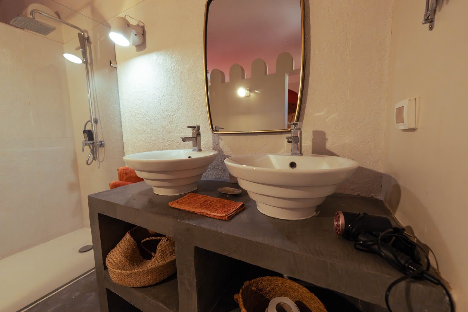 Une salle de bain avec deux lavabos, une douche et un miroir.