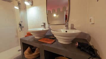 Une salle de bain avec deux lavabos, une douche et un miroir.