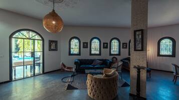 A spacious living room with a large sofa, a round ottoman, and a hanging light fixture.
