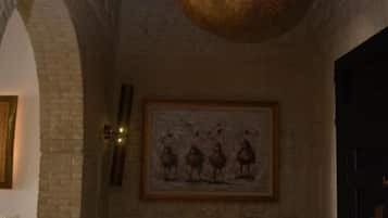 A room with a vaulted ceiling, a hanging spherical light fixture, a framed artwork on the wall, and a bench with a cushioned seat.