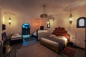 A bedroom with a bed, a desk, a chair, and a wardrobe. There are also two windows with decorative frames.