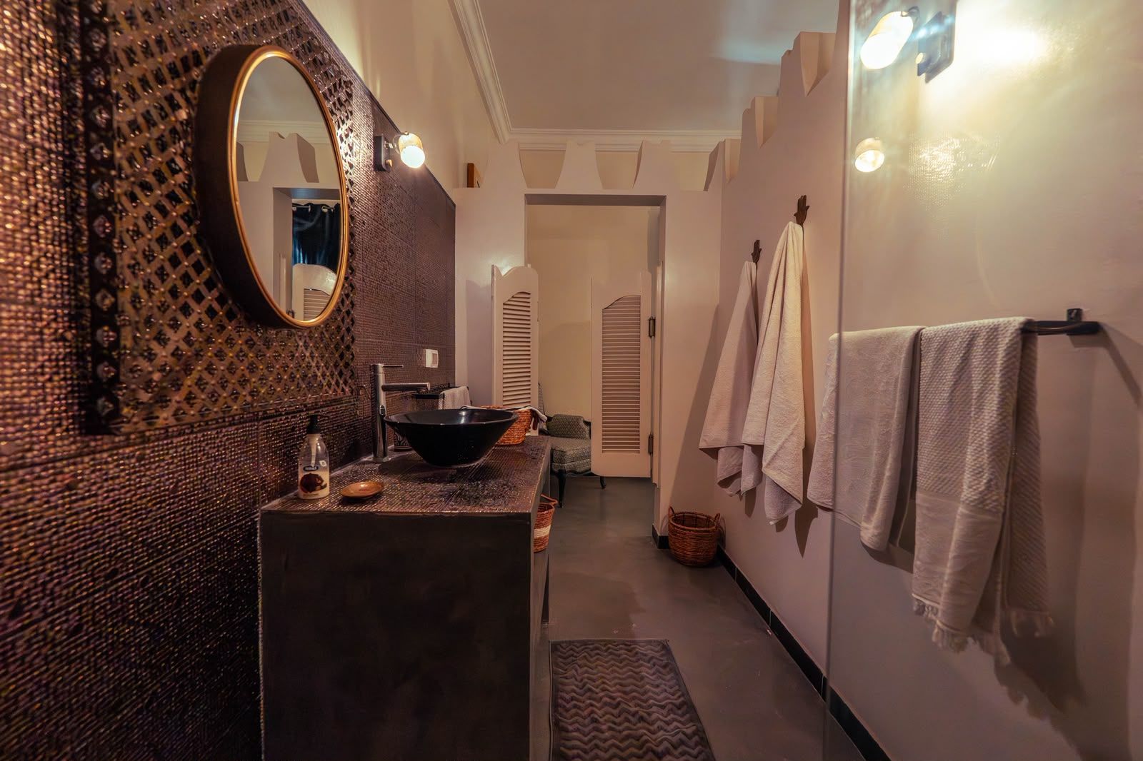 A bathroom with a black sink, a mirror, and towels hanging on the wall.