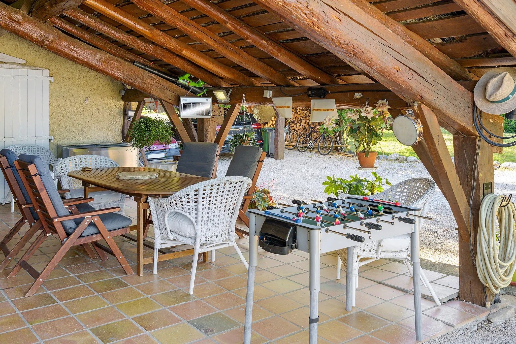 Un patio al aire libre con una mesa de fútbol de mesa, sillas de mimbre y una mesa con un juego de mesa.