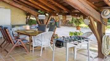 Un patio al aire libre con una mesa de fútbol de mesa, sillas de mimbre y una mesa con un juego de mesa.