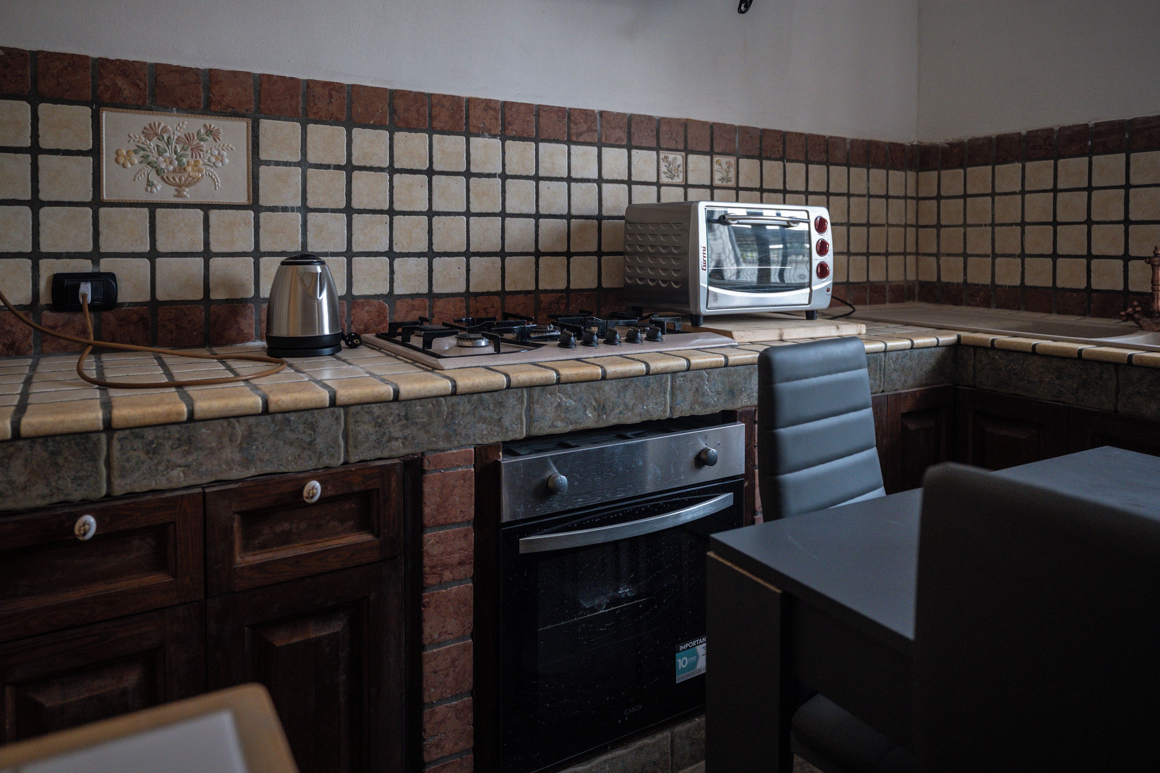A kitchen with a gas stove, a toaster, and a kettle.