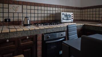 A kitchen with a gas stove, a toaster, and a kettle.