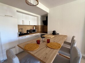 Eine moderne Küche mit weißen Schränken, einer Holz Arbeitsplatte und einem Esstisch mit zwei Platzdeckchen.