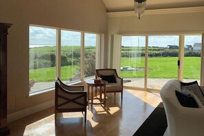 A spacious living room with large windows, a wooden floor, and a white sofa.