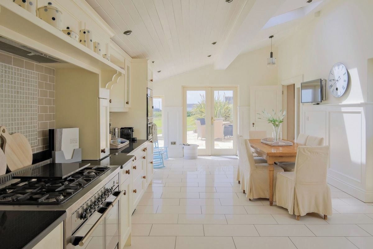 A kitchen with a stove, cabinets, and a dining area with chairs and a table.