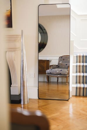 Et værelse med et stort spejl, der viser en stol og en sofa med et mønster.