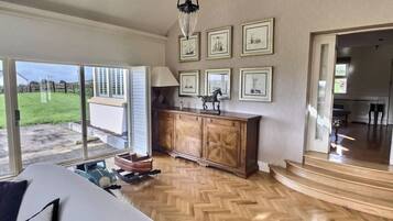 Une pièce avec un parquet en chevrons, un lit avec des oreillers, une armoire en bois et des œuvres d’art encadrées accrochées au mur.