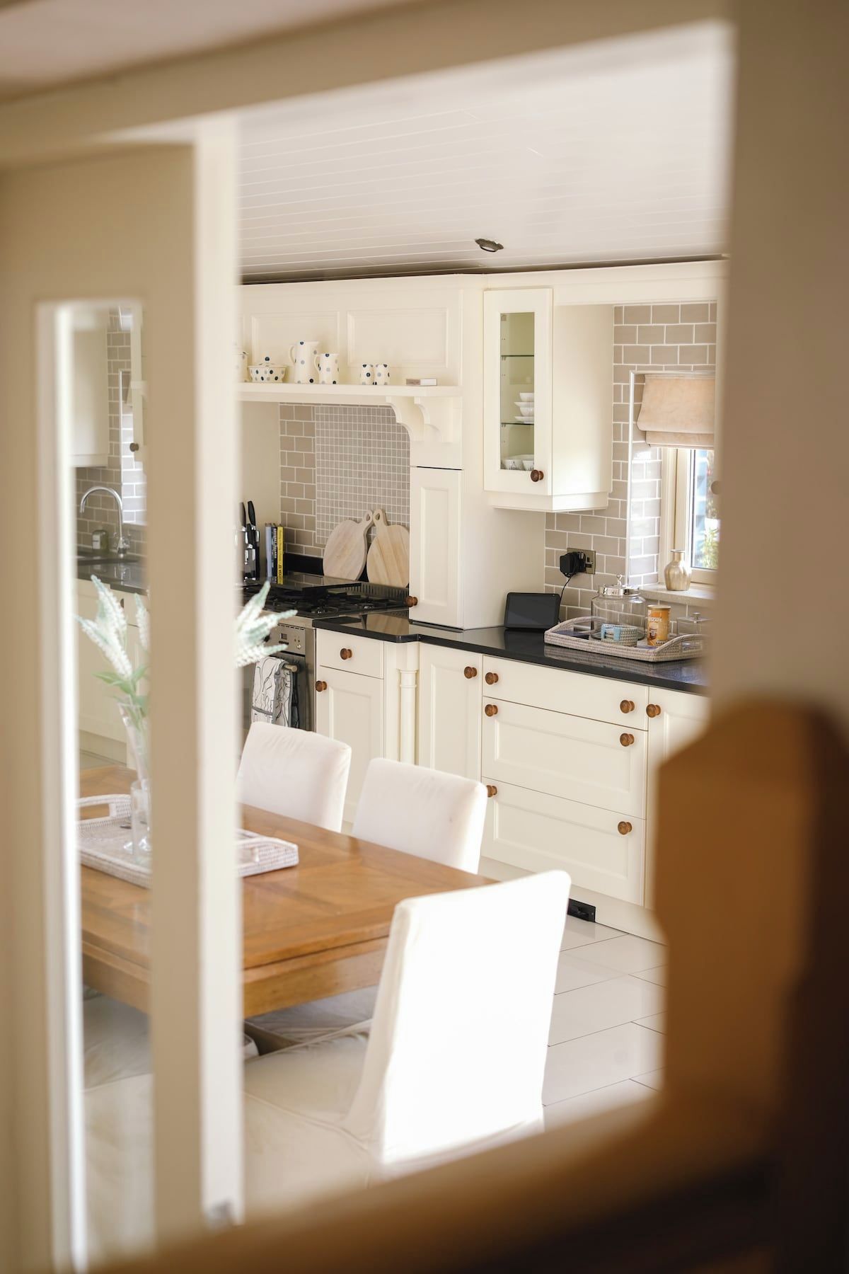 Een moderne keuken met witte kasten, een houten eettafel en uitzicht op de eetruimte.