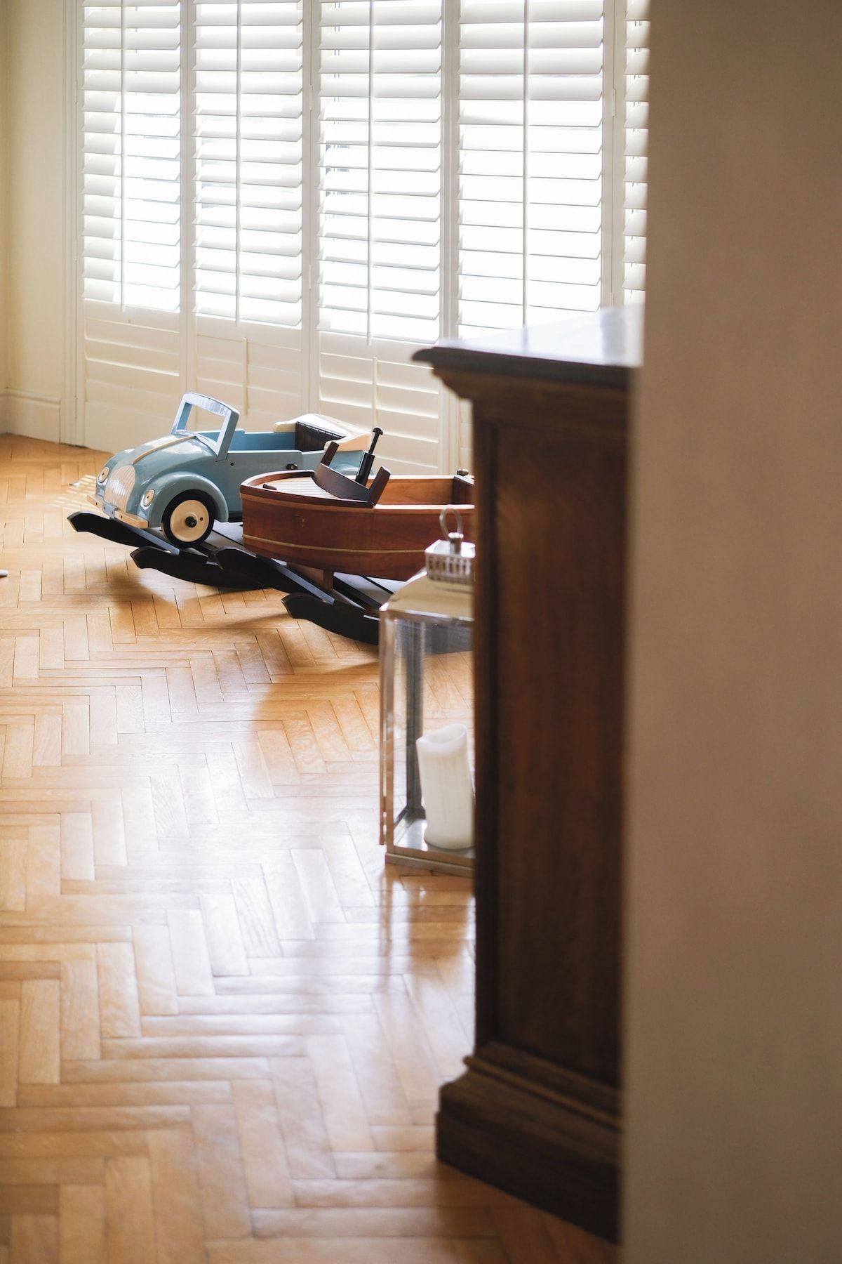 Ein Zimmer mit Holzboden, einem blauen Spielzeugauto und einem Holzschrank.