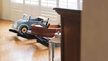 Ein Zimmer mit Holzboden, einem blauen Spielzeugauto und einem Holzschrank.