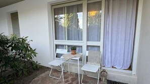 A small outdoor seating area with two white chairs, a table, and a potted plant. - Renovated apartment with a terrace and parking (Houlgate)