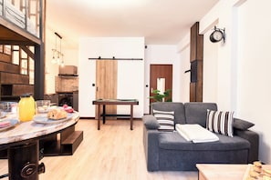 Ein modernes Wohnzimmer mit Billardtisch, einer Couch und einem Essbereich mit gedecktem Tisch.