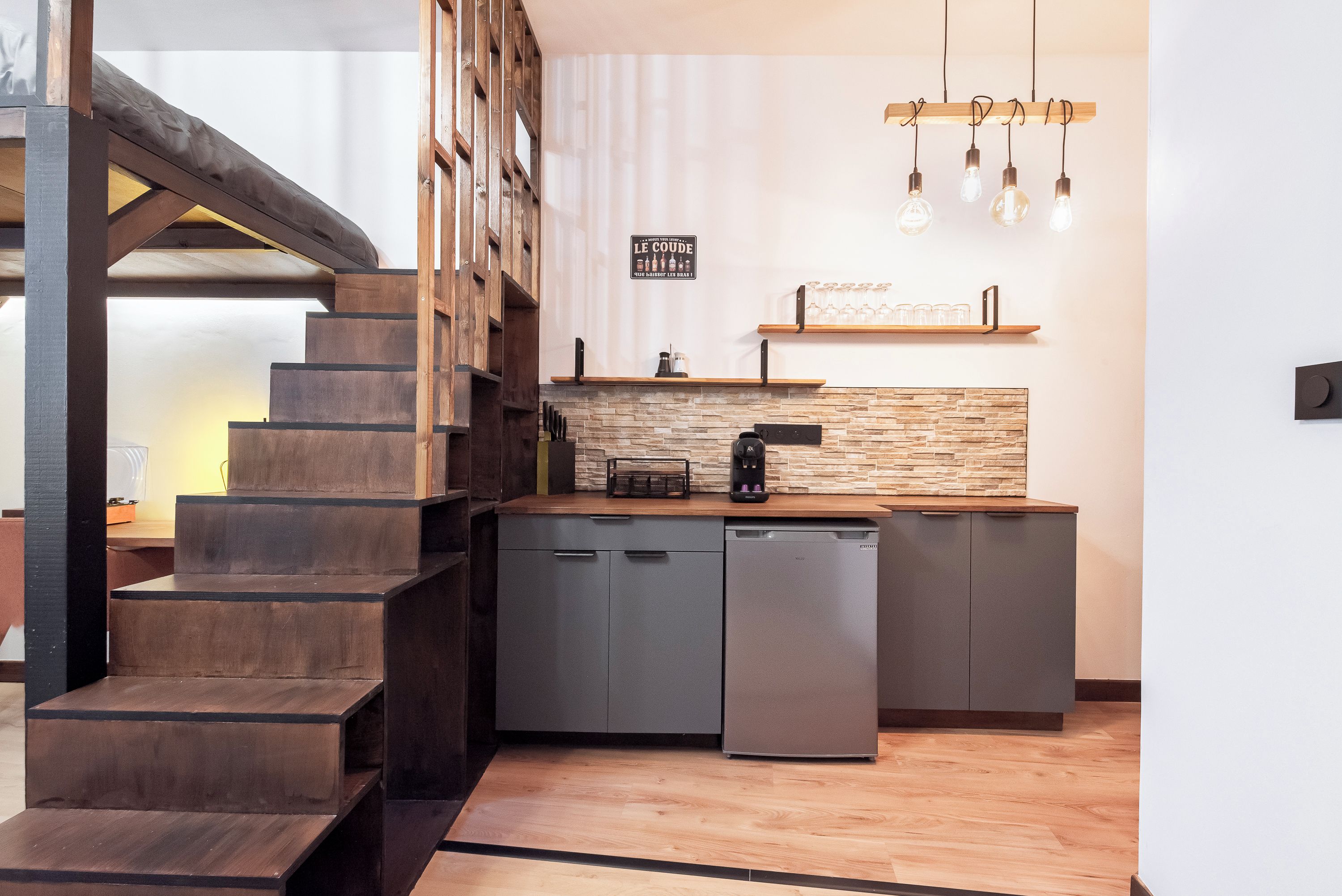Une cuisine moderne équipée d’un lave-vaisselle intégré, d’une machine à café et d’un escalier en bois.
