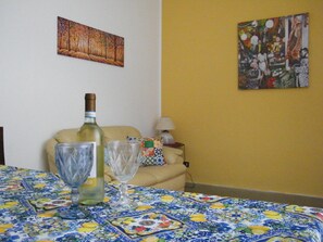 Et værelse med en borddug med mønster, en flaske og to glas på et bord.