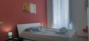A bedroom with a bed, a bedside lamp, a window with curtains, and a painting on the wall. - Holiday Home 'Mi manda Picone da Lolli's Liberty Apartment' (Palermo)