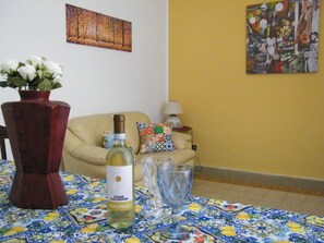 Ein Esstisch mit einer Weinflasche, einem Glas und einer Blumenvase.