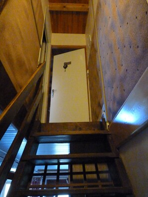 Eine Holztreppe führt zu einer weißen Tür mit Schlüsselloch.