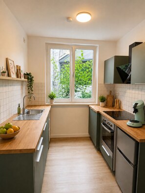 A modern kitchen with a window, stainless steel appliances, and a wooden countertop.