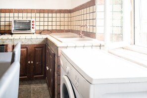 Une buanderie équipée d’un lave-linge, d’un sèche-linge, d’un évier et d’un four grille-pain.