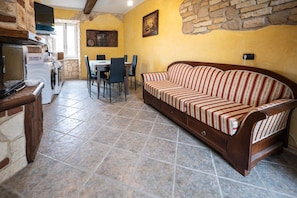 Un coin repas avec une table et des chaises, un canapé et un mur en pierre.