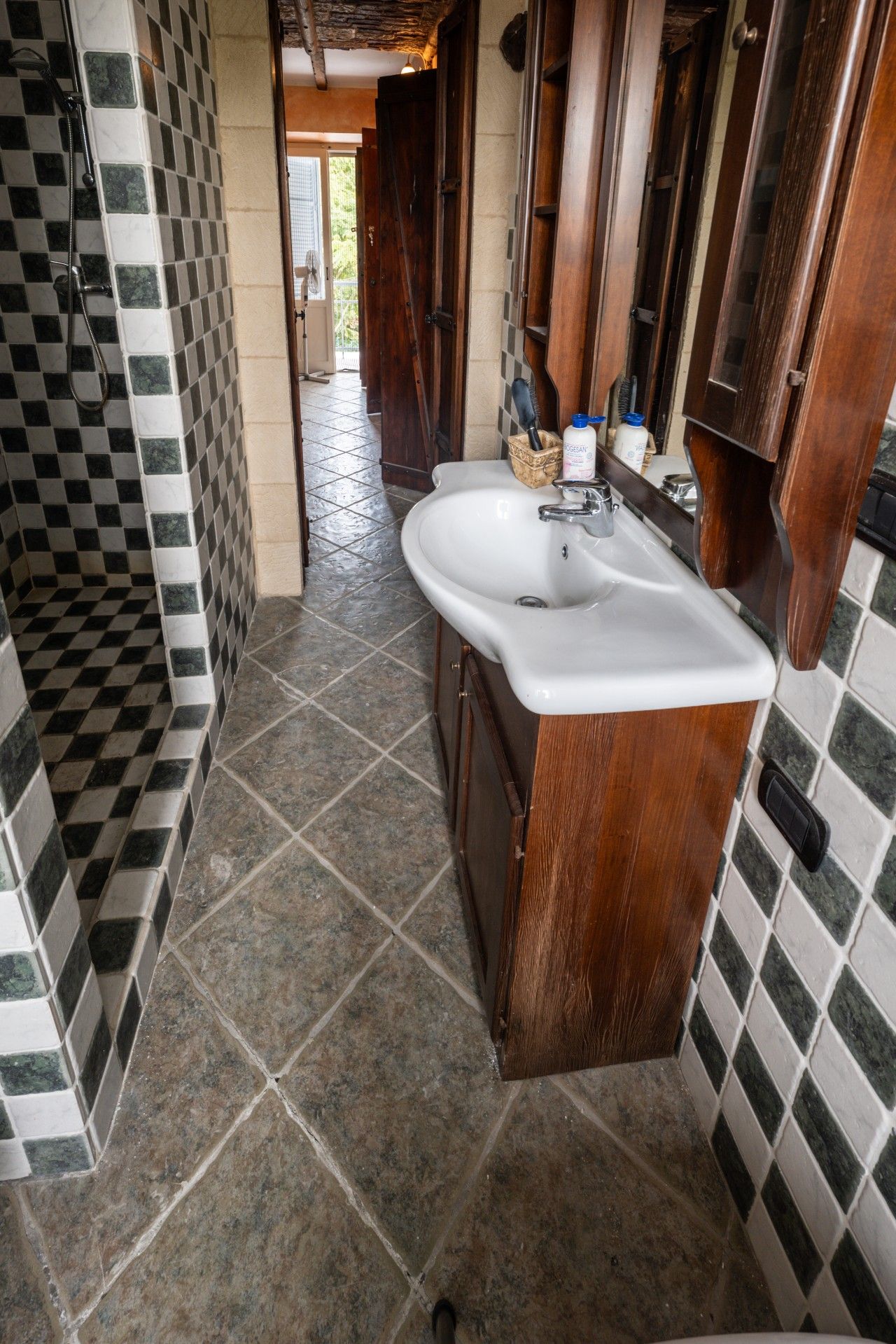 Une salle de bain avec un lavabo blanc, des meubles en bois et des murs recouverts de carreaux à motifs.