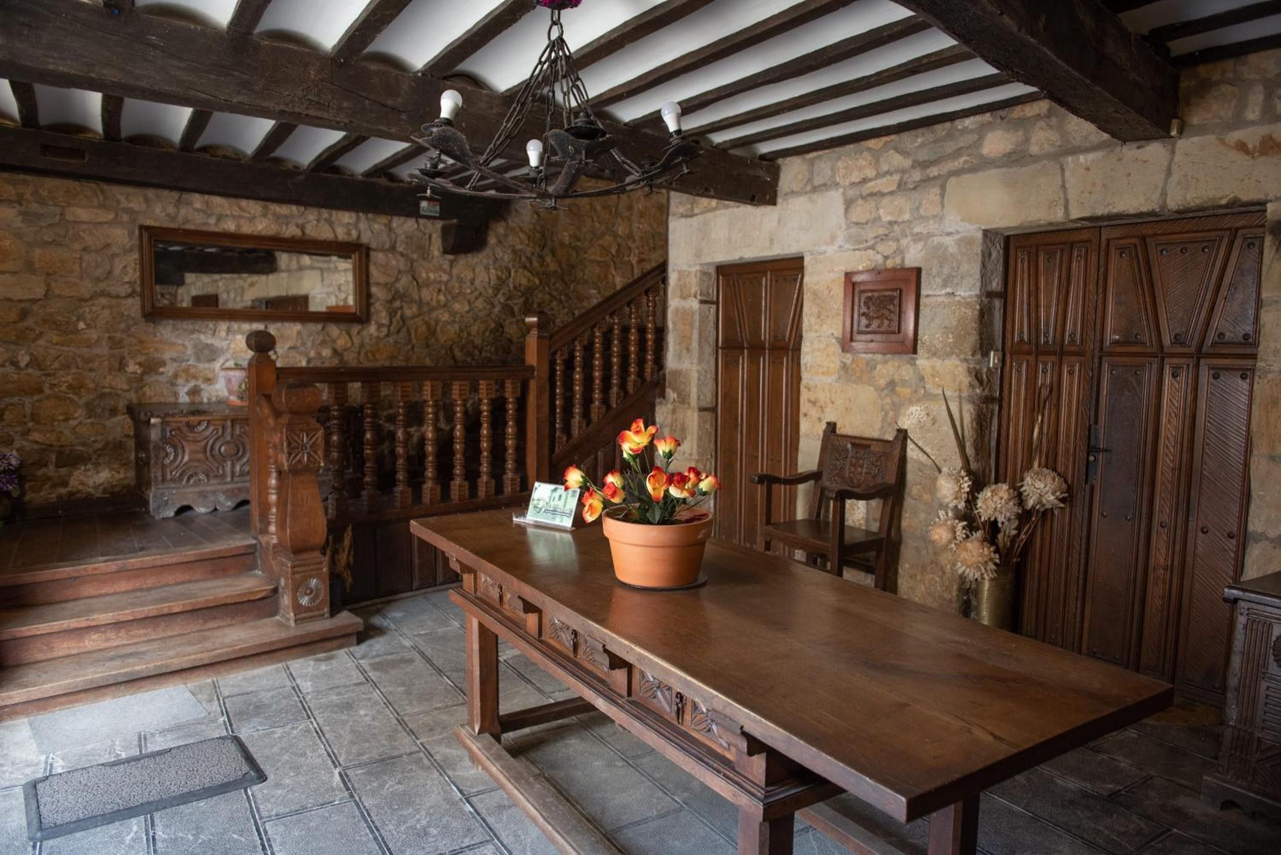 Un intérieur rustique avec une table en bois, un escalier et des murs en pierre.