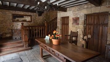 Un intérieur rustique avec une table en bois, un escalier et des murs en pierre.