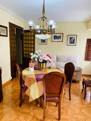 Ein Essbereich mit einem Tisch für vier Personen, einer Chandelier und einer Couch im Hintergrund.