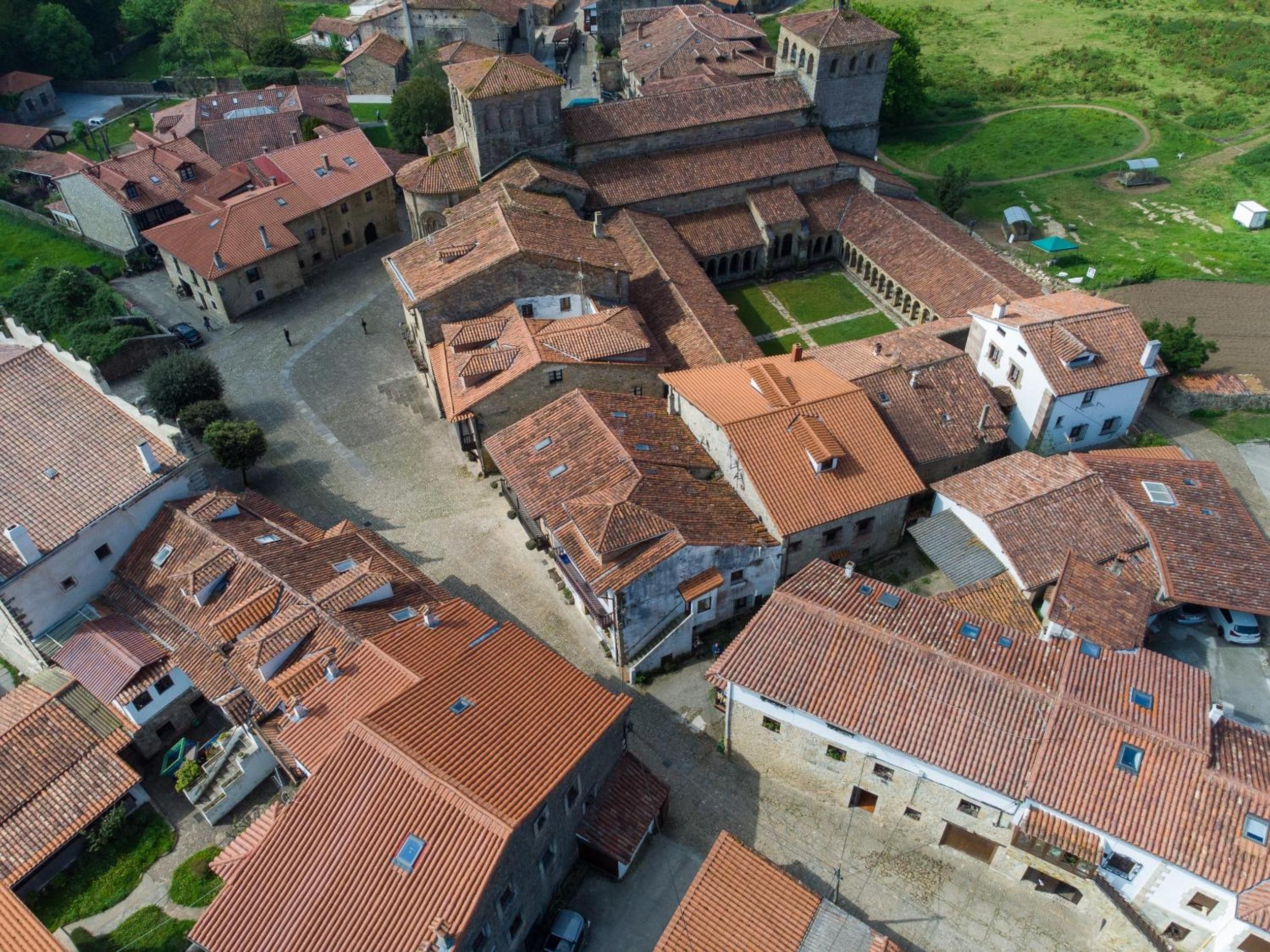 Vista aérea de un pueblo histórico con edificios muy juntos y techos de tejas rojas, y una plaza central.